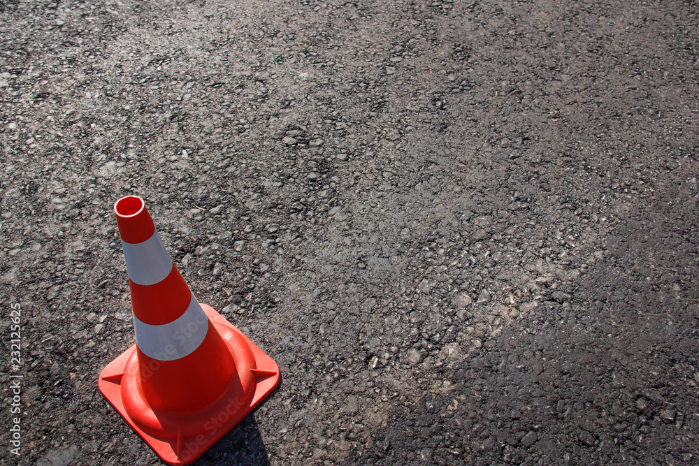traffic cone, with white and orange stripes on gray asphalt, copy space traffic cone, with white and orange stripes on gray asphalt, copy space