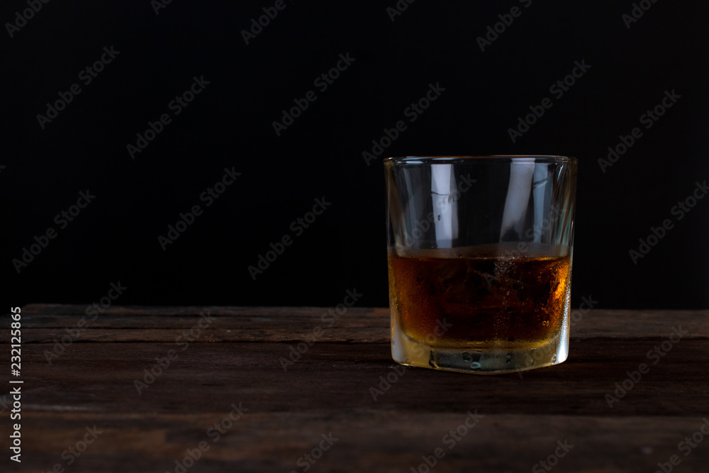 Glass of alcohol scotch whiskey with ice on wooden table and black background Glass of alcohol scotch whiskey with ice on wooden table and black background