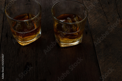 Glass of alcohol scotch whiskey with ice on wooden table and black background © BNMK0819