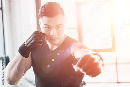young asian sportsman wearing boxing gloves in sunlight