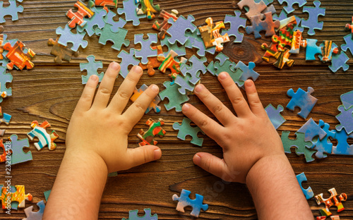 scattered puzzle pieces, baby hands on wooden table background. preschool education.
