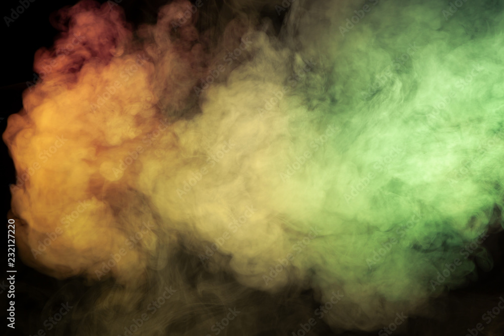 Multicolored smoke of red yellow and green colors from a vap scattering on a black isolated background