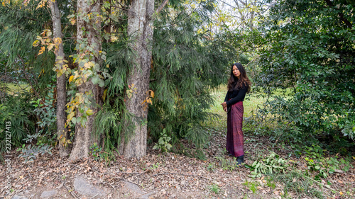 Thai woman standing in forest next to trees in sarong
