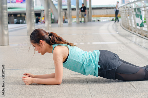 Young woman relaxing after doing push ups, woman exercising on fitness in street city