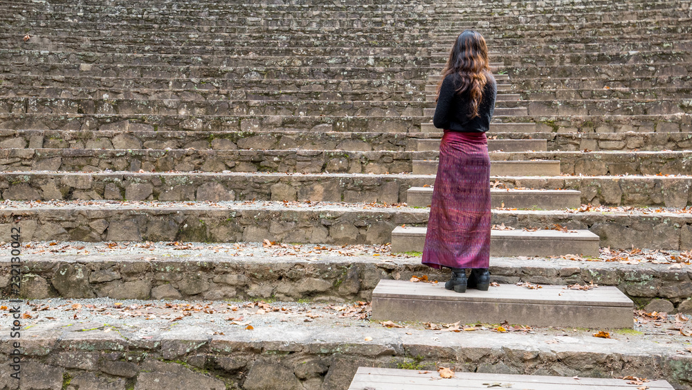 woman in sarong in amphitheater standing on steps looking away from stage