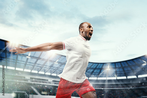 The football african player in motion on the field of stadium at day. The professional football, soccer player and human emotions concept. The win, winner, victory concept