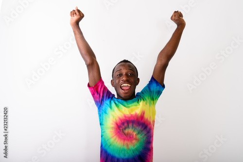 Studio shot of young happy black African man with both arms rais