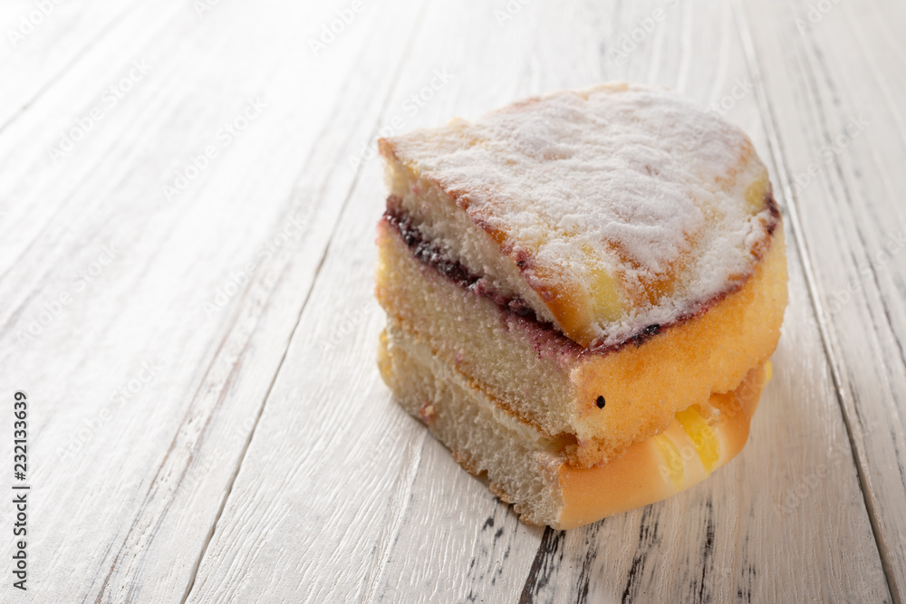 multi-layer sponge cake on white wood background multi-layer sponge cake on white wood background