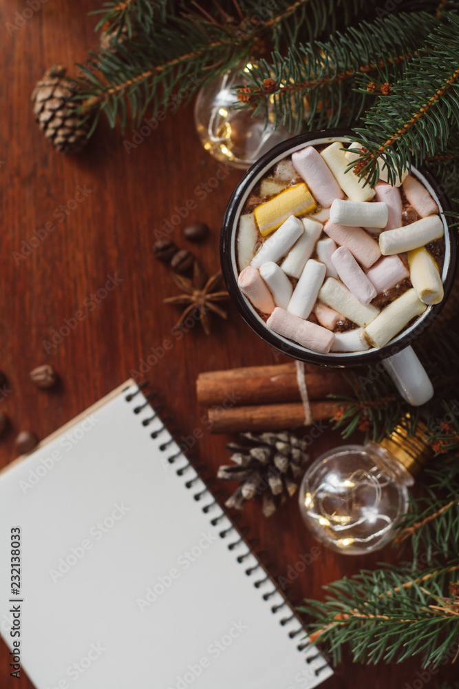Chocolate or cocoa with marshmallow,  notebook and  garland on a wooden background.