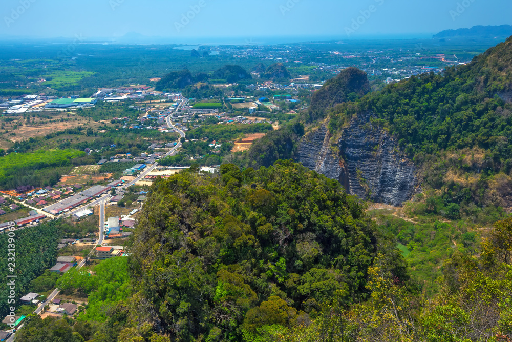 Panoramic view from the top of the mountain to the neighborhood, green fields, forests, road, houses from a bird's flight. Tham Sua Thamsua Cave Temple Enlightenment Center, Krabi, Thailand.