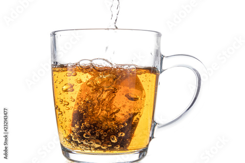 Brewing a tea bag in a transparent mug with sugar on a white background, a storm in a glass