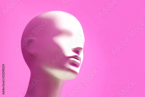 Head of white mannequin on pink background. Faceless girl.
