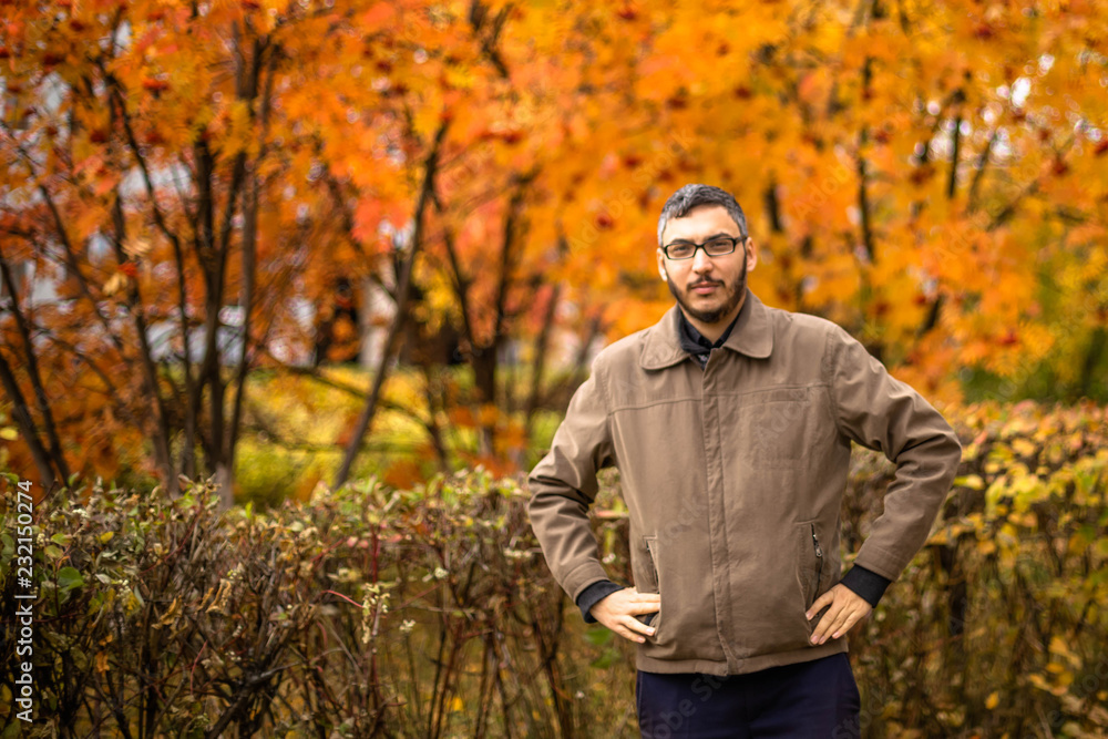 Young man with beard and mustache wearing glasses in brown jacket Young man with beard and mustache wearing glasses in brown jacket