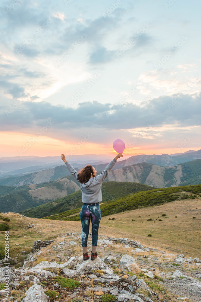 Woman with balloon standing in sunset mountains Woman with balloon standing in sunset mountains