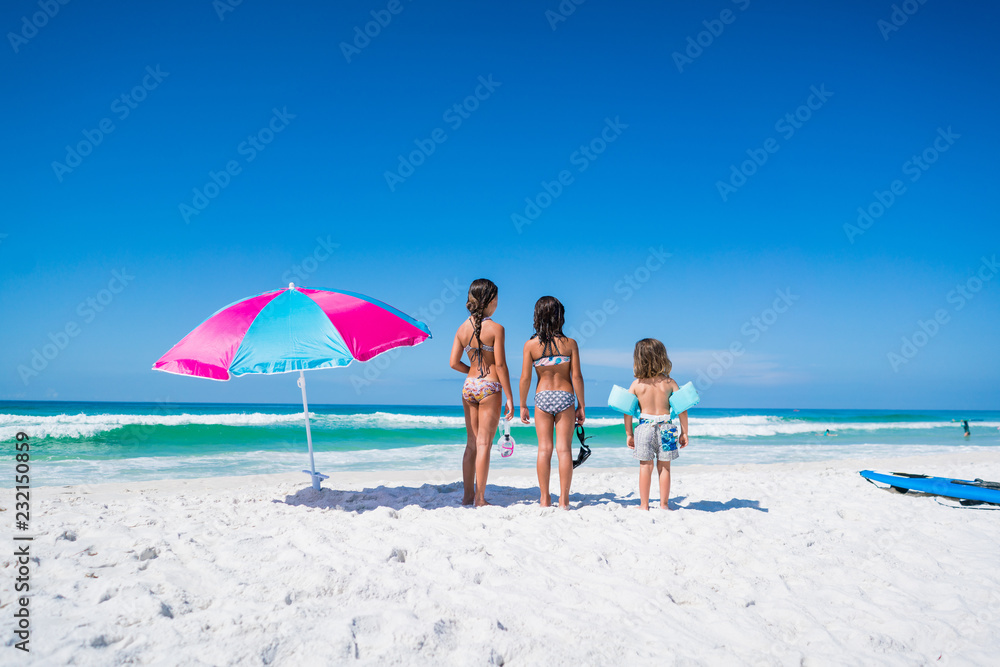 Three Kids on the Beach with an Umbrella Three Kids on the Beach with an Umbrella