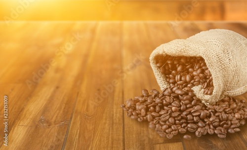 Coffee beans spilling from sack on white background