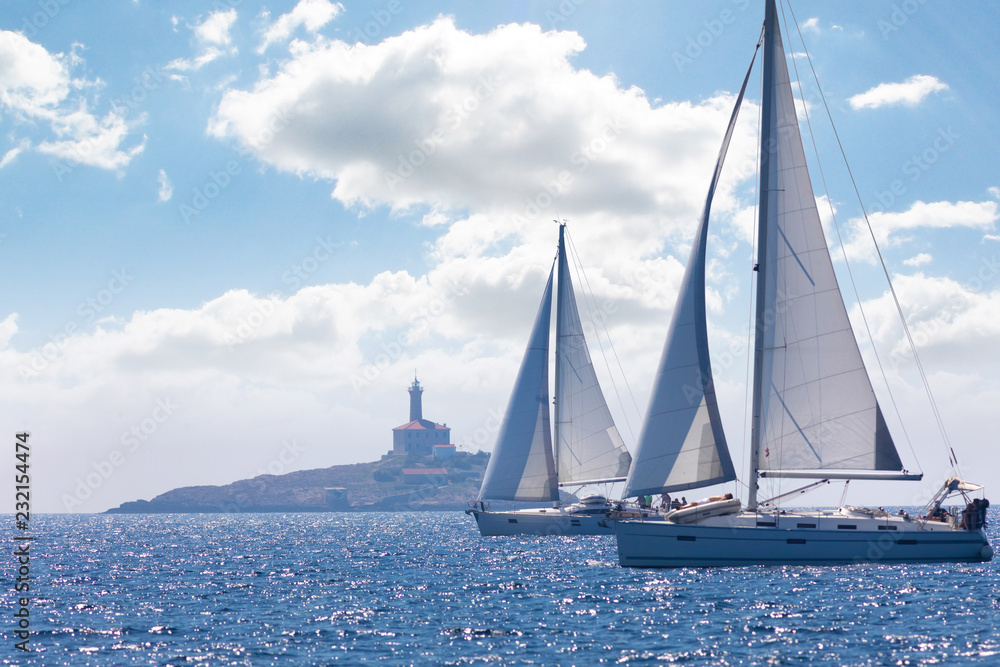 Obraz premium two sailing ships near a lighthouse in summer day, Croatia