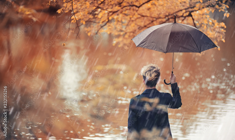 Fototapeta premium Autumn rainy weather and a young man with an umbrella
