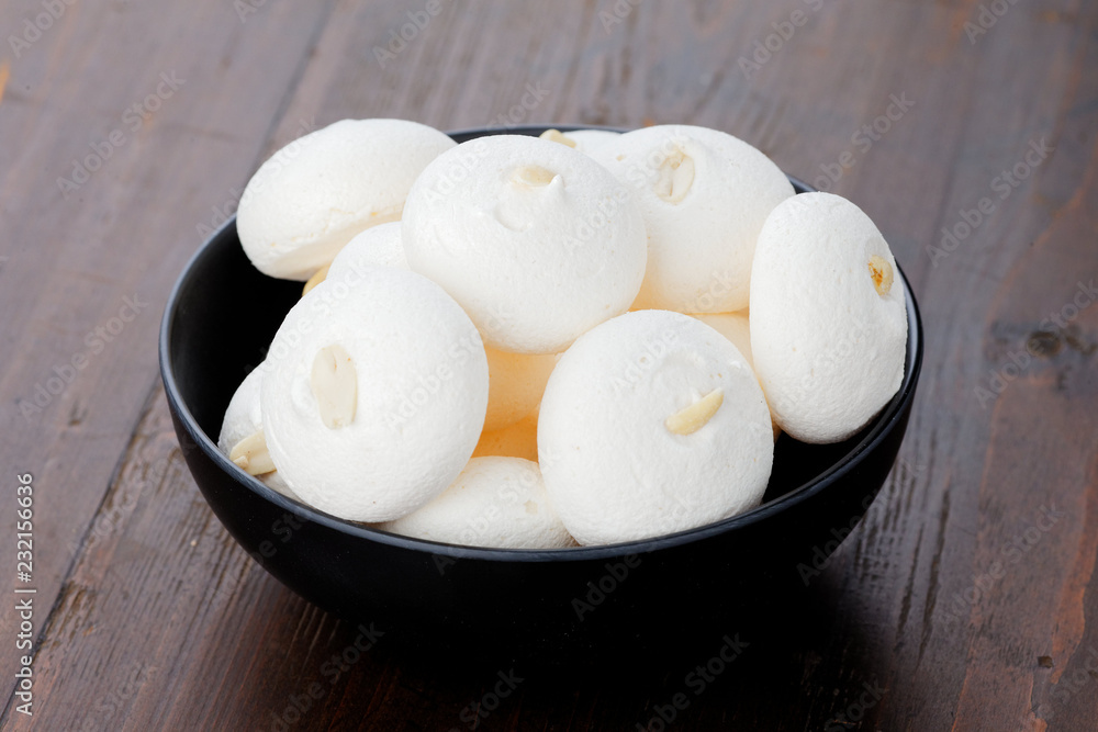 White meringues on a black plate on a wooden background. Meringues with peanuts. White meringues on a black plate on a wooden background. Meringues with peanuts.