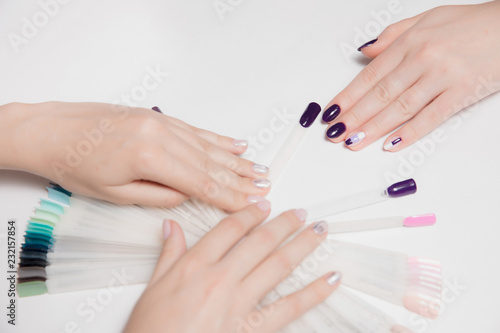 Velvety well-groomed female hands with light by sudovym nail Polish craftsmen and purple manicure client