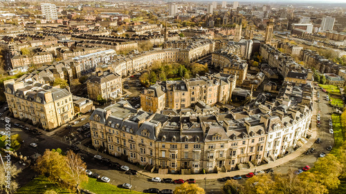 Low level aerial image over the autumn foliage of trees in Kelvingrove Park, Glasgow, to the elegant buildings of Park Circus.