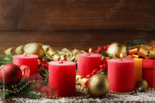 Christmas candles with fir-tree branches and baubles on wooden table