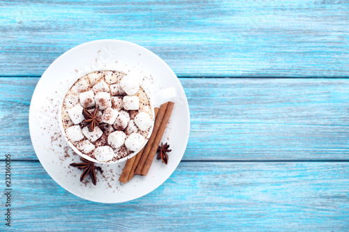Cappuccino with marshmallows, cinnamon and star anise on blue wooden table