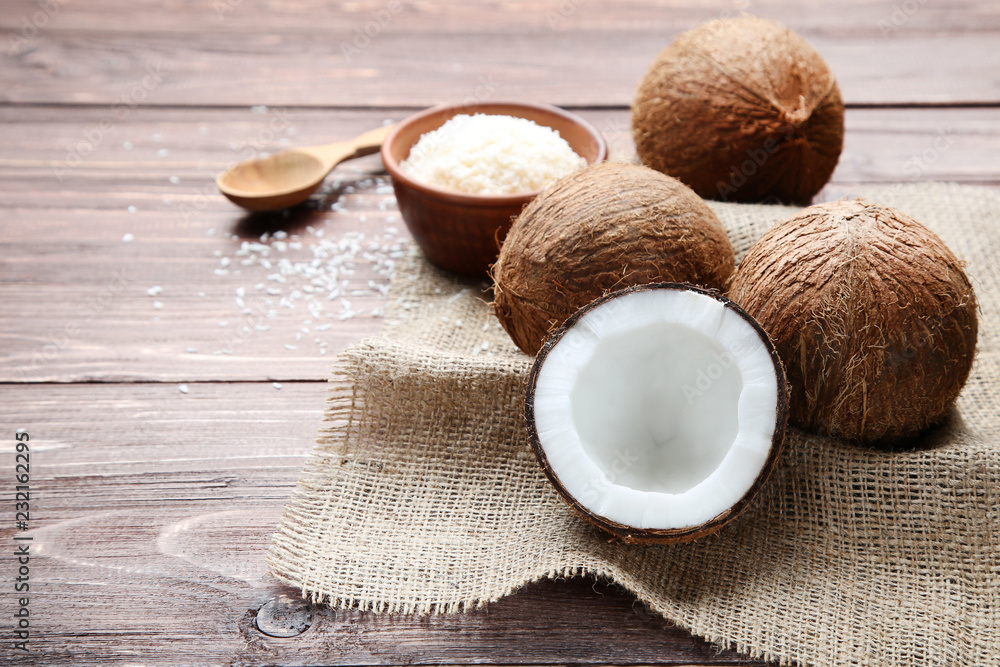 Ripe coconuts with flakes in bowl on brown wooden table Ripe coconuts with flakes in bowl on brown wooden table