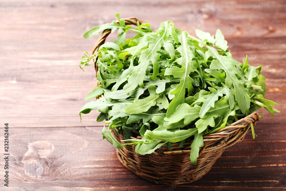 Green arugula leafs in basket on brown wooden table Green arugula leafs in basket on brown wooden table