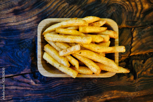 Crispy crispy fries on a rustic wooden table. French fries in a serving platter.