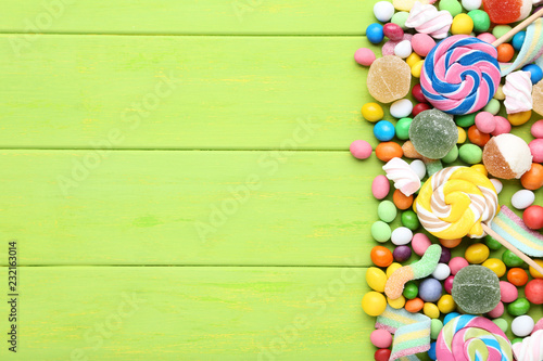 Sweet candies and lollipops on green wooden table