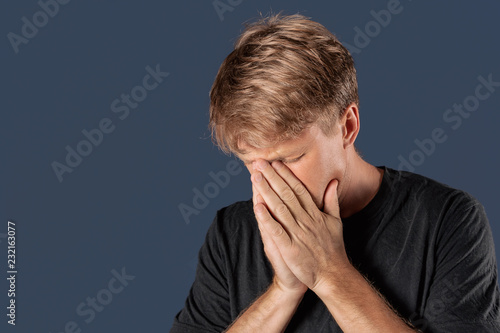 Stressed and sad man covering his face with hands. Sadness, despair, tragedy concept