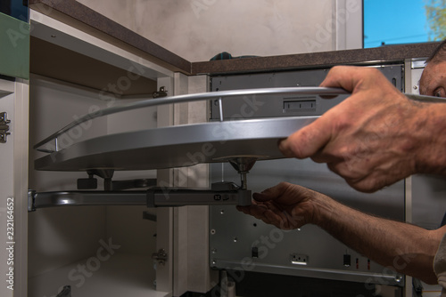 A furniture carpenter builds a movable shelf part in a corner cabinet. Concept: craft and service