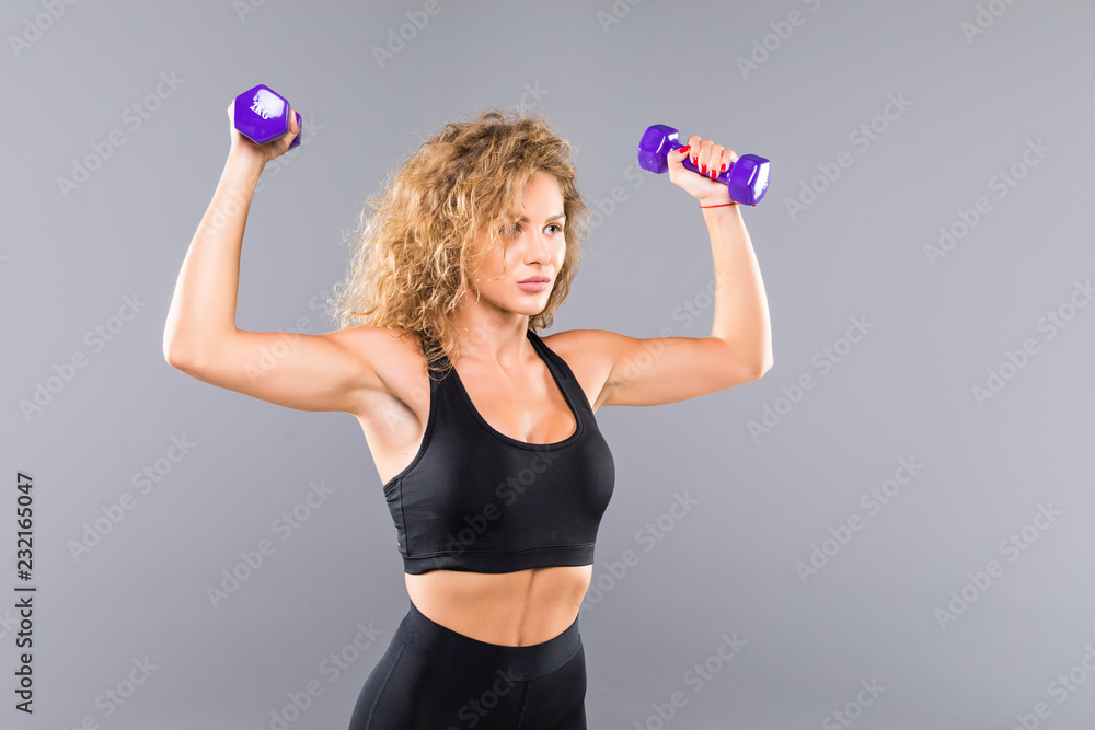 Sporty woman does the exercises with dumbbells on white background. Muscular woman in sportswear on white background. Strength and motivation. Sporty woman does the exercises with dumbbells on white background. Muscular woman in sportswear on white background. Strength and motivation.