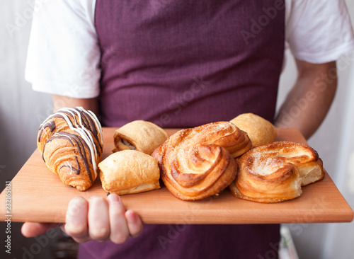 Baker showing tray of fresh croissant and buns in the kitchen