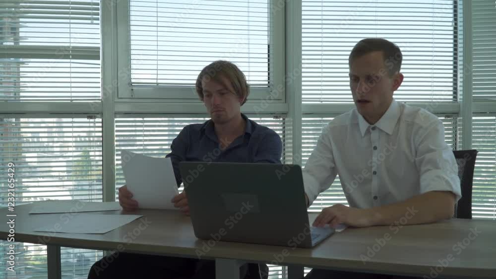 Two office workers discuss information form netbook Two office workers discuss information form netbook