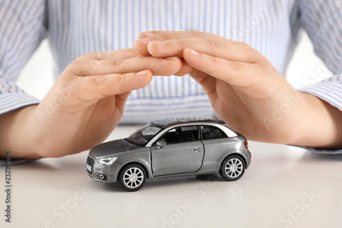 Female insurance agent covering toy car at table, closeup