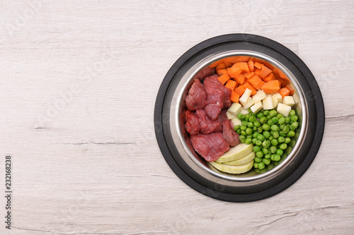 Bowl with organic dog food on light background, top view. Space for text