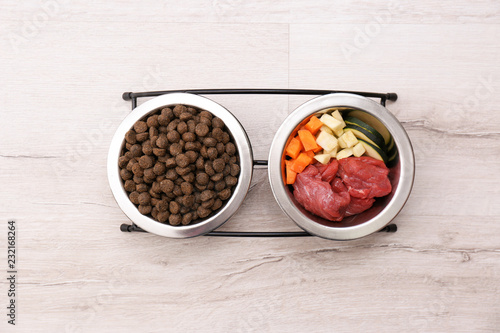 Bowls with dry and natural dog food on light background, top view