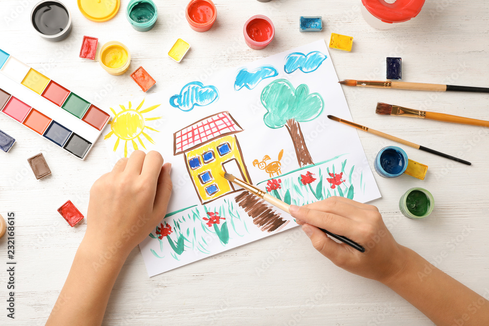 Naklejka premium Girl painting picture of house on table, top view