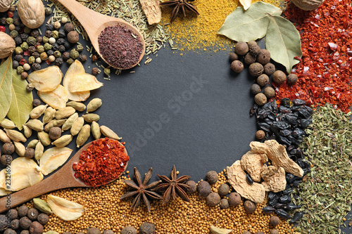 Frame made of different aromatic spices on dark background, top view with space for text