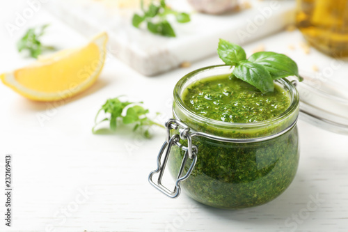 Fotografia Homemade basil pesto sauce in glass jar on table