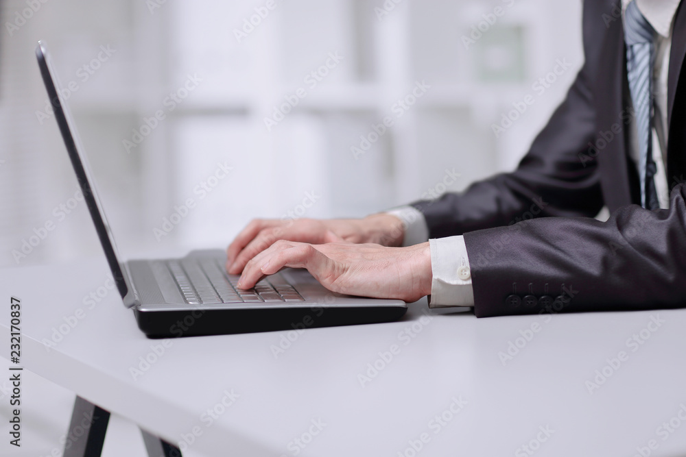 close up. businessman typing on laptop while sitting at table close up. businessman typing on laptop while sitting at table