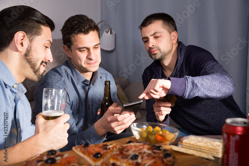 friends looking at phone while drinking beer