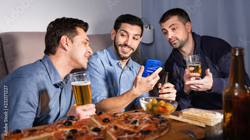 Male friends sitting with phone at home