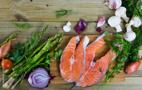 Food frame of salmon steaks, vegetables, mushrooms on wooden surface photo