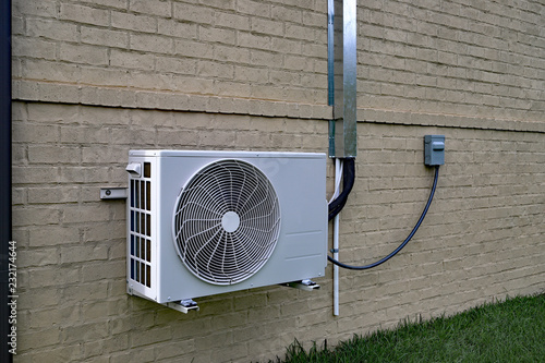 Air Conditioner mini split system next to home with brick wall photo