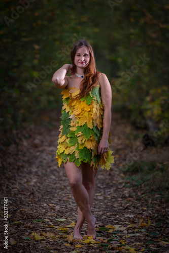 Attractive girl with long hair wearing dress made from colorful leaves in the autumn forest, Brno, Czech Republic photo