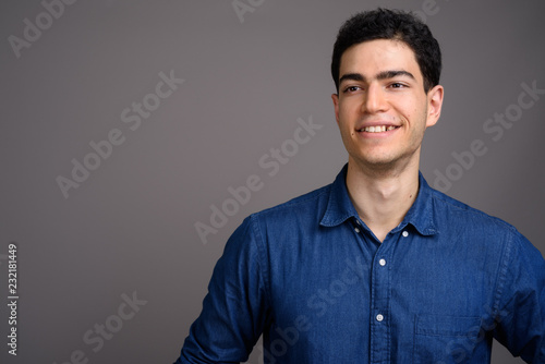 Portrait of young handsome businessman against gray background