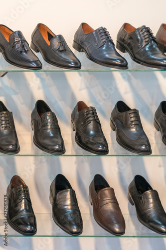 Men's leather shoes on the shelf in the store. Racks in the store of clothes and accessories. Shelves with stylish men's shoes. Many classic shoes and boots. vertical photo